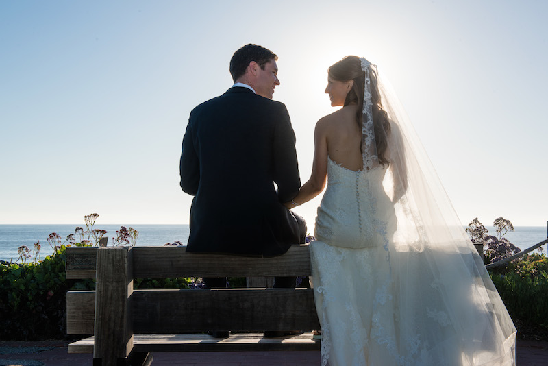 bride and groom on bench, ocean background