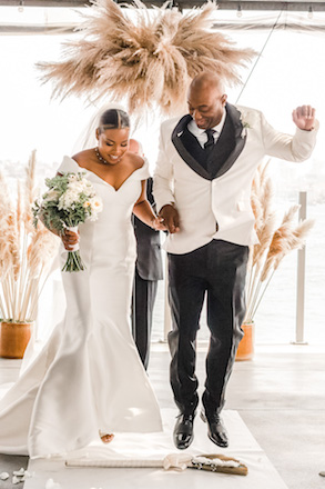 bride and groom jumping broom